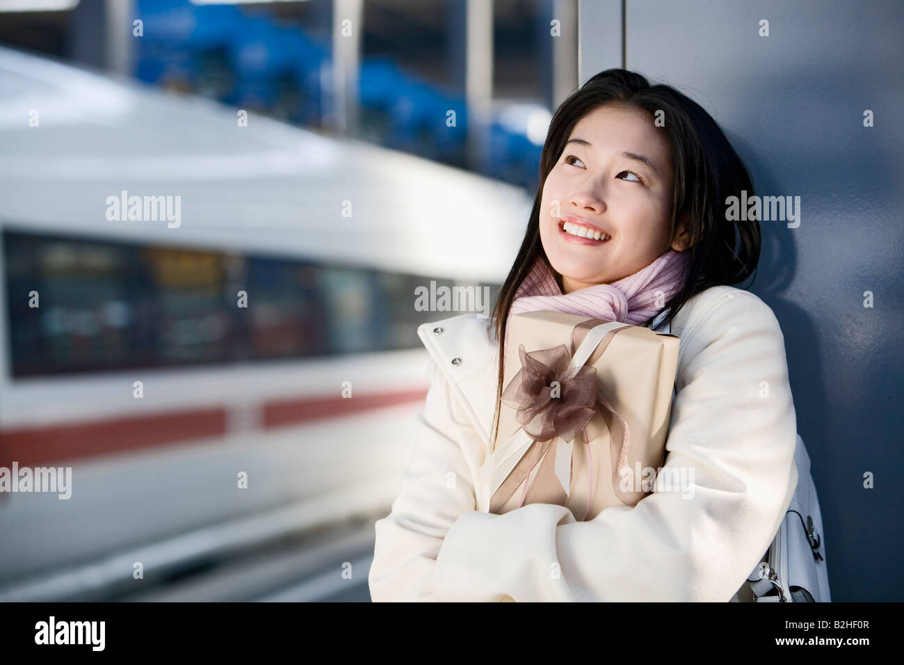 Giovane donna giapponese in attesa con la presente alla stazione ferroviaria Foto Stock