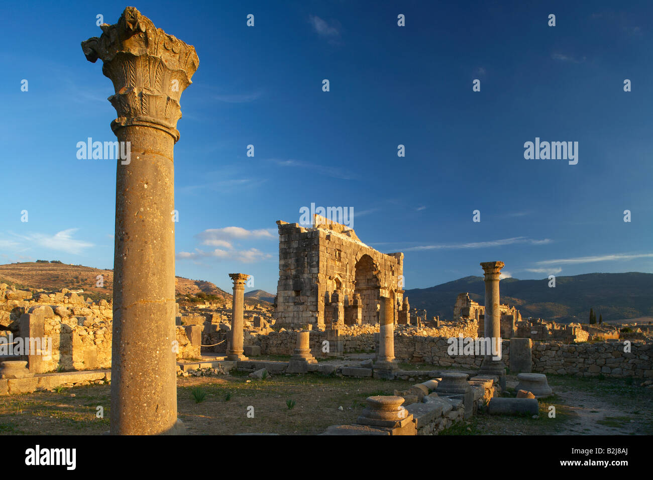 Le antiche rovine romane con l arco trionfale e Basilica oltre a Volubilis, Marocco Foto Stock