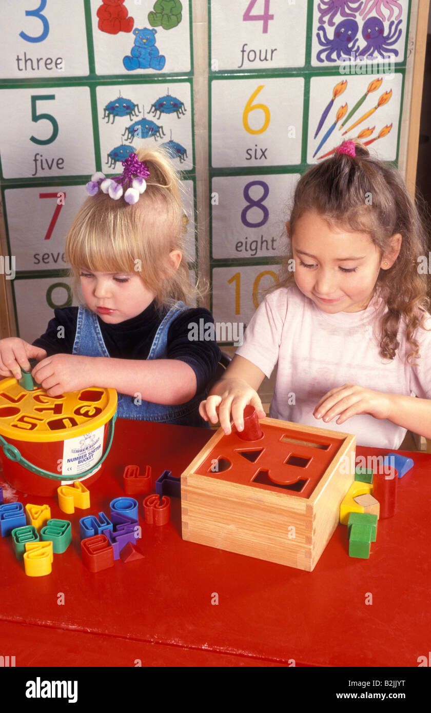 2 bambine giocando con i puzzle di smistamento a playschool Foto Stock