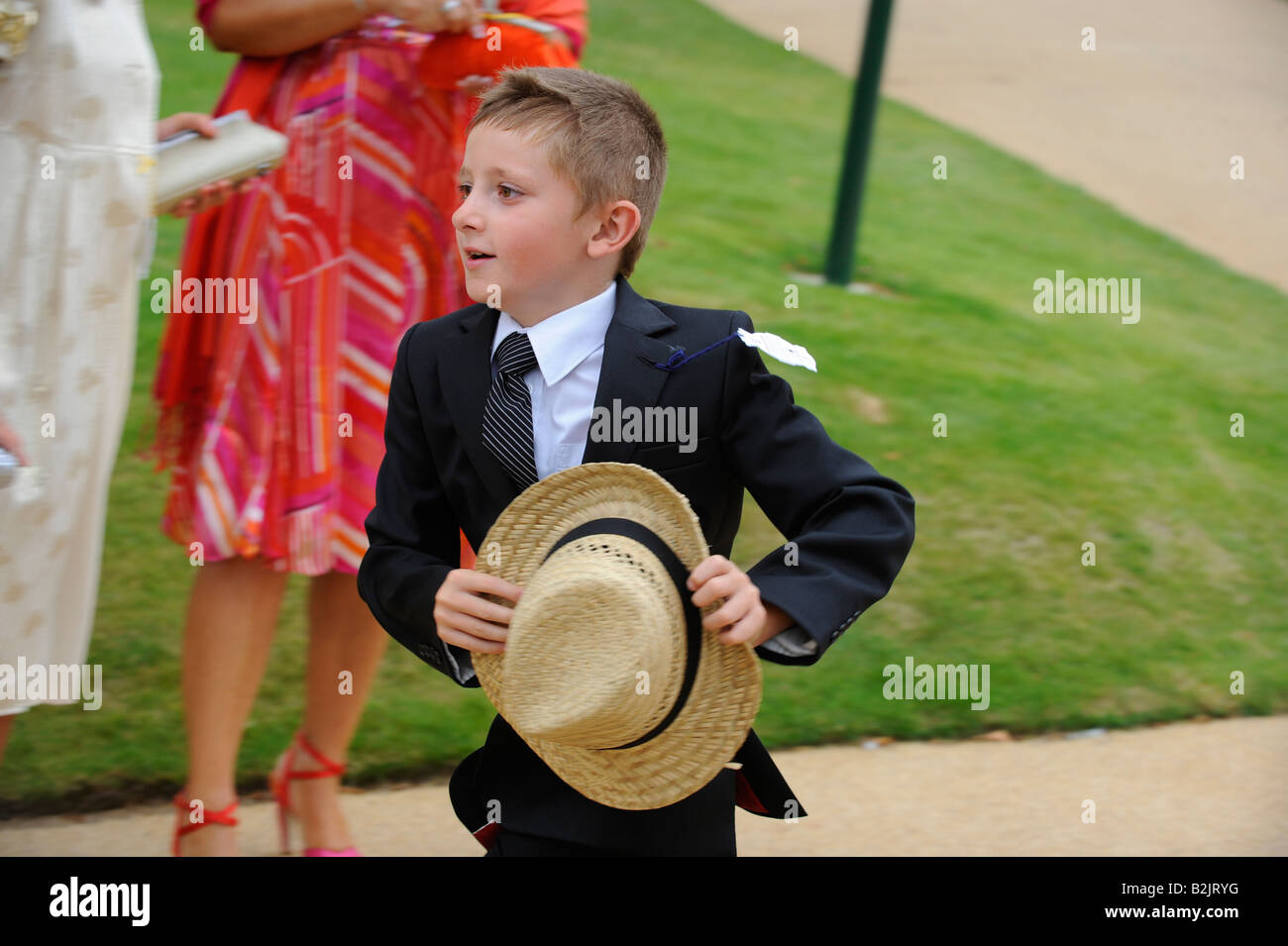 Glorioso giorno delle Signore di Goodwood - un ragazzo che corre tenendo il suo cappello di paglia. Foto Stock
