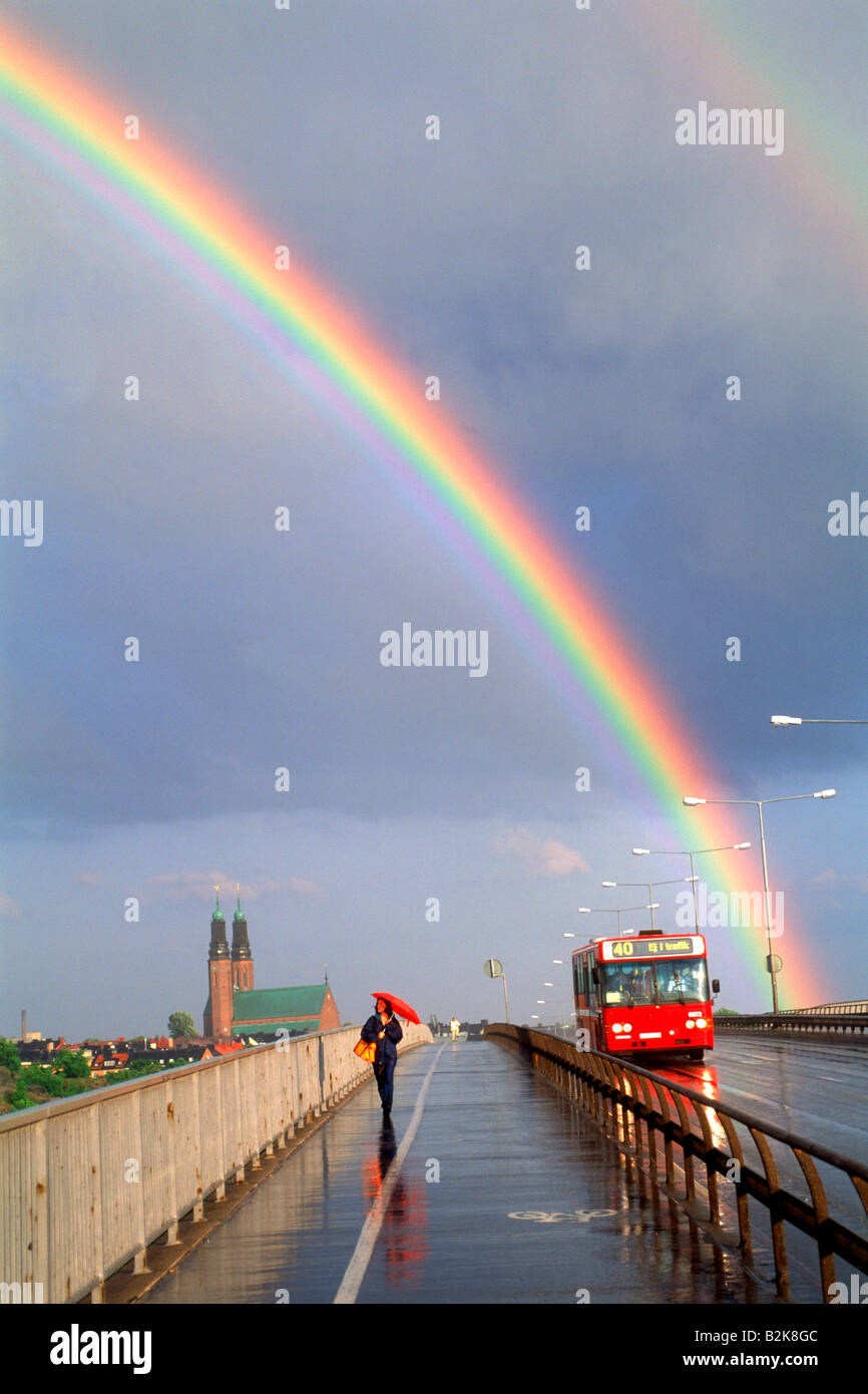 Donna con ombrello rosso camminando sul Ponte Vasterbro con autobus di città in rainbows a Stoccolma Foto Stock