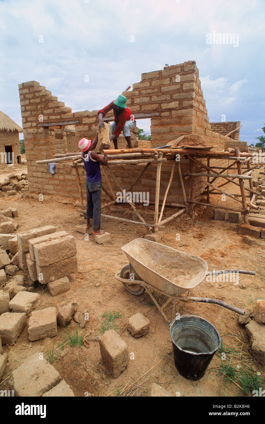 Gli uomini africani edificio scala piccola casa di mattoni sulla piantagione di tabacco in Zimbabwe Foto Stock