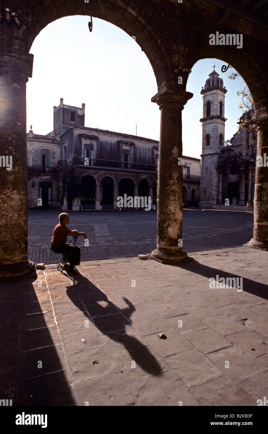 Uomo solitario seduto su una sedia sotto uno degli archi di piazza del Duomo a l'Avana, Cuba Foto Stock