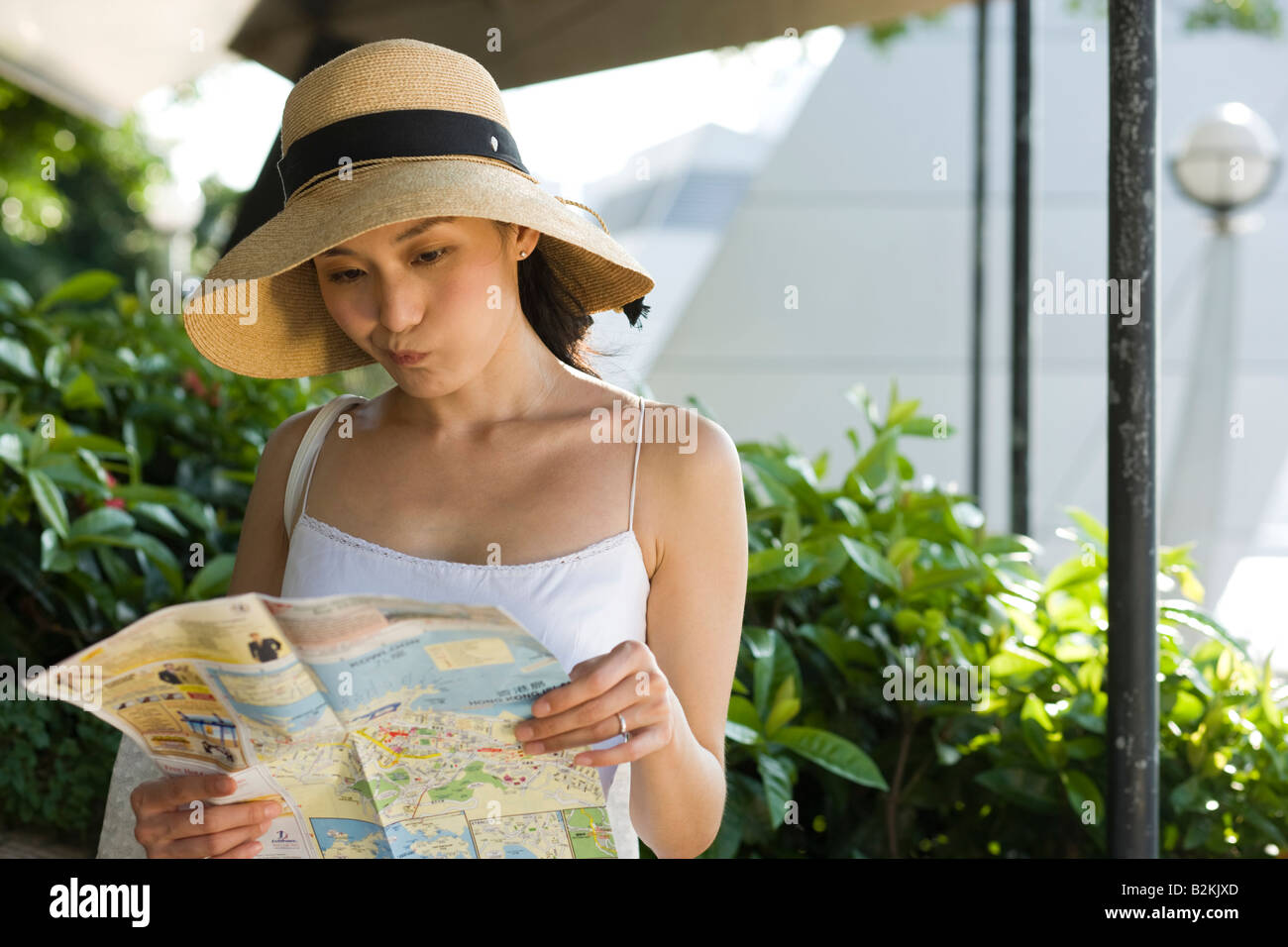Giovane donna che indossa un cappello per il sole e guardando una mappa Foto Stock