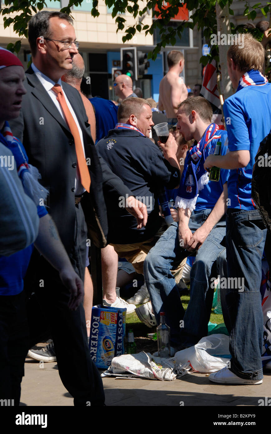 Business man passa da come Glasgow Rangers fan drink nel centro della città di Manchester nel loro migliaia prima di finale di Euro 2008 Foto Stock