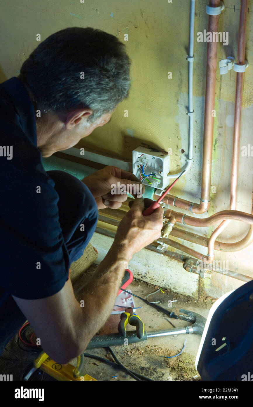 Elettricista lavorando sul sistema di riscaldamento Foto Stock