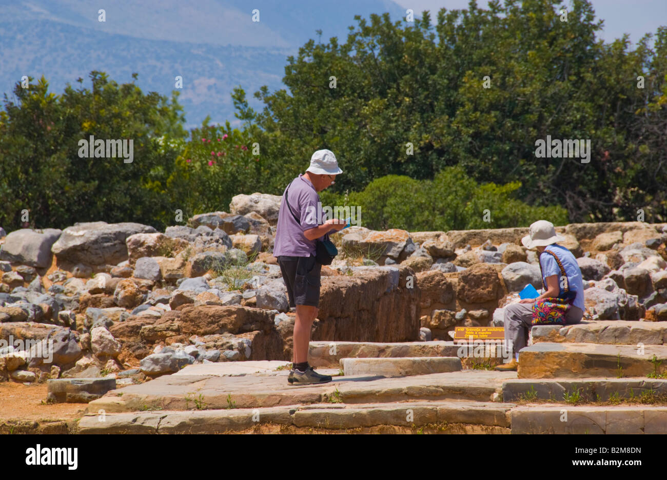 I turisti in cerca di rovine del palazzo minoico distrutto da un incendio nel 1450 BC a Malia sul Greco isola mediterranea di Creta Foto Stock