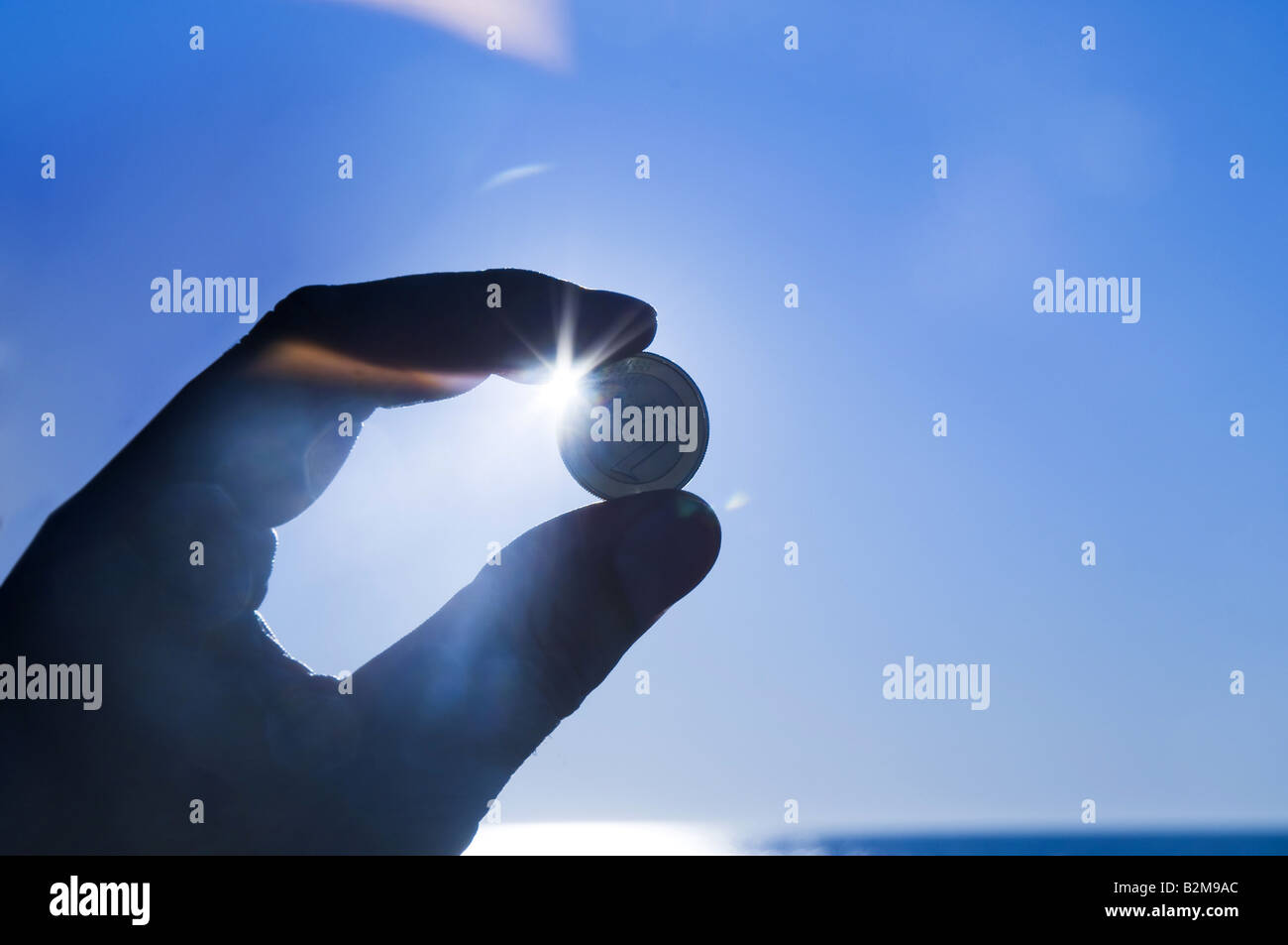 Mano azienda Euro moneta contro il sole Foto Stock