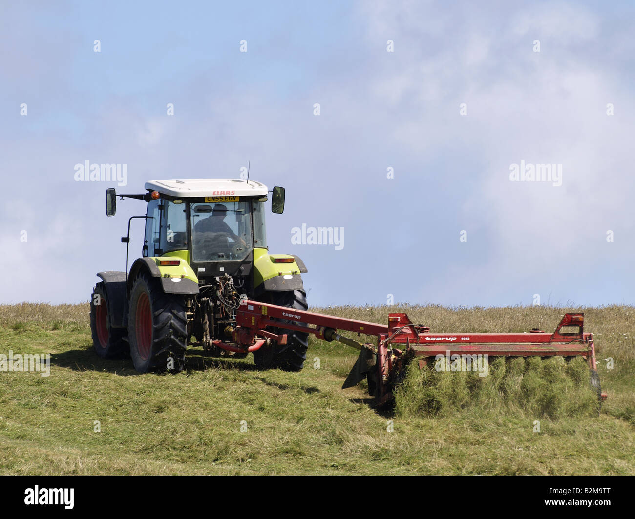 Agricoltore il taglio dell'erba in un trattore Foto Stock