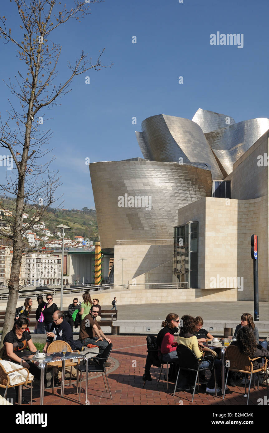 I giovani seduti alla caffetteria all'aperto con tavoli di fronte il Museo Guggenheim museo Galleria d'arte Bilbao Spagna Foto Stock