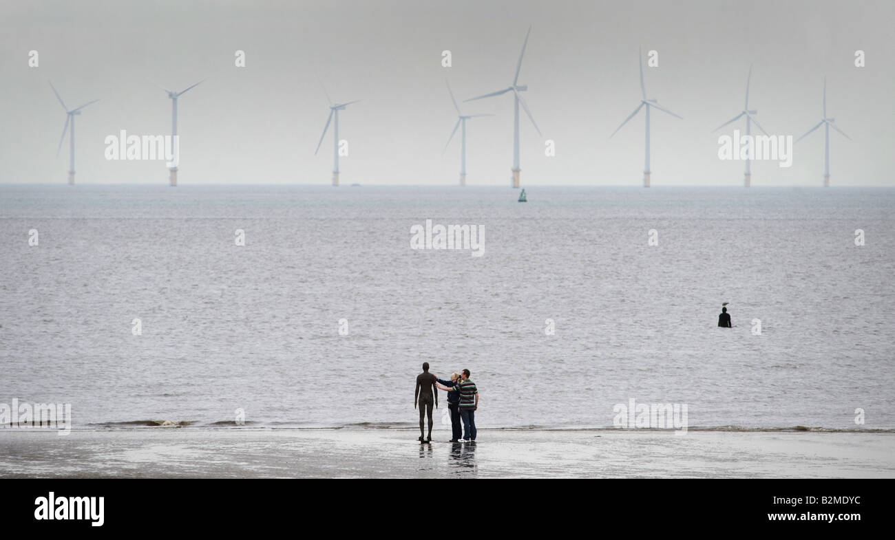 Un paio di toccare uno di gli uomini di ferro statue in Crosby spiaggia vicino Liverpool creato dall'artista Antony Gormley,UK,Inghilterra. Foto Stock