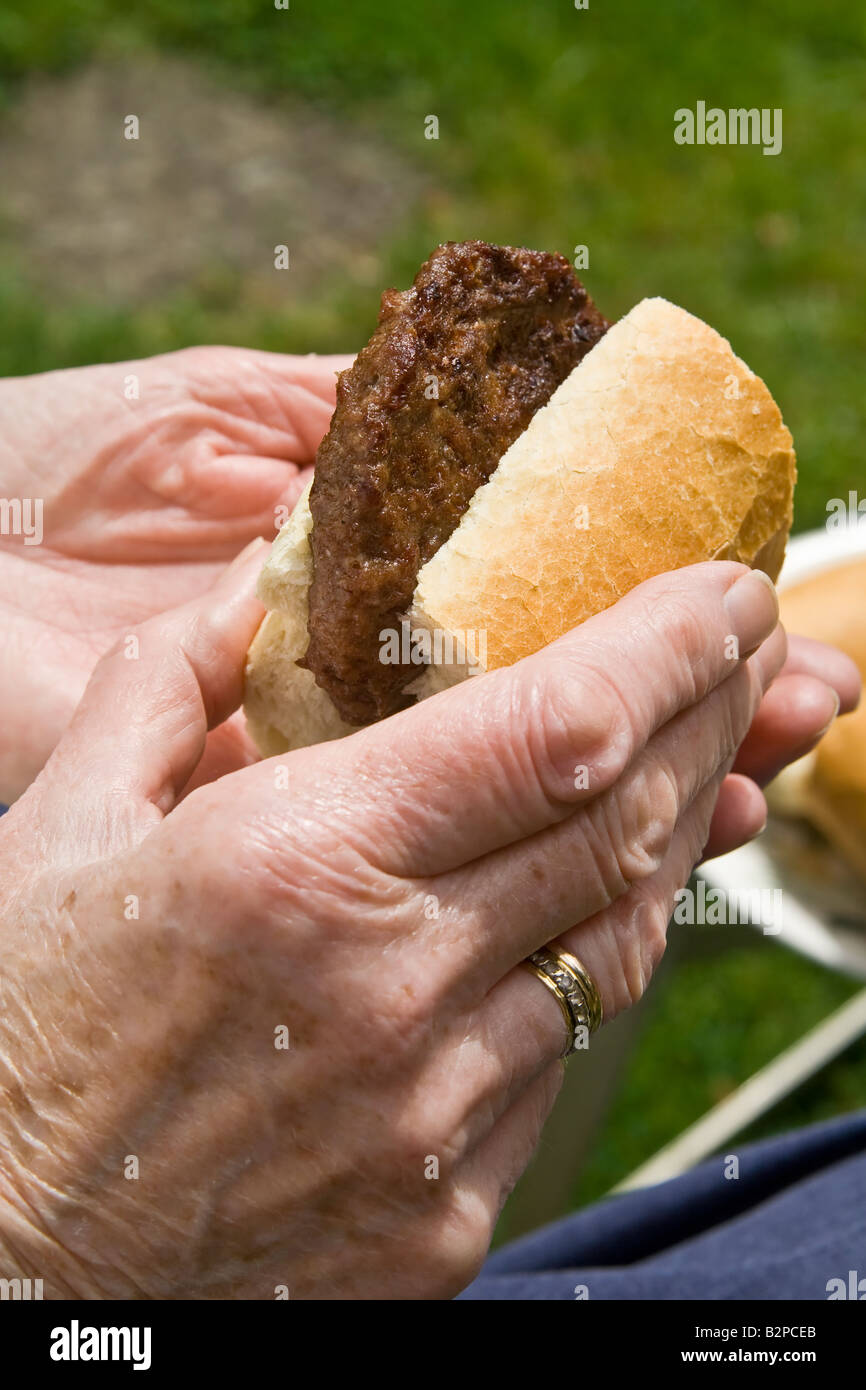 Una vecchia donna a un barbecue, UK. Foto Stock