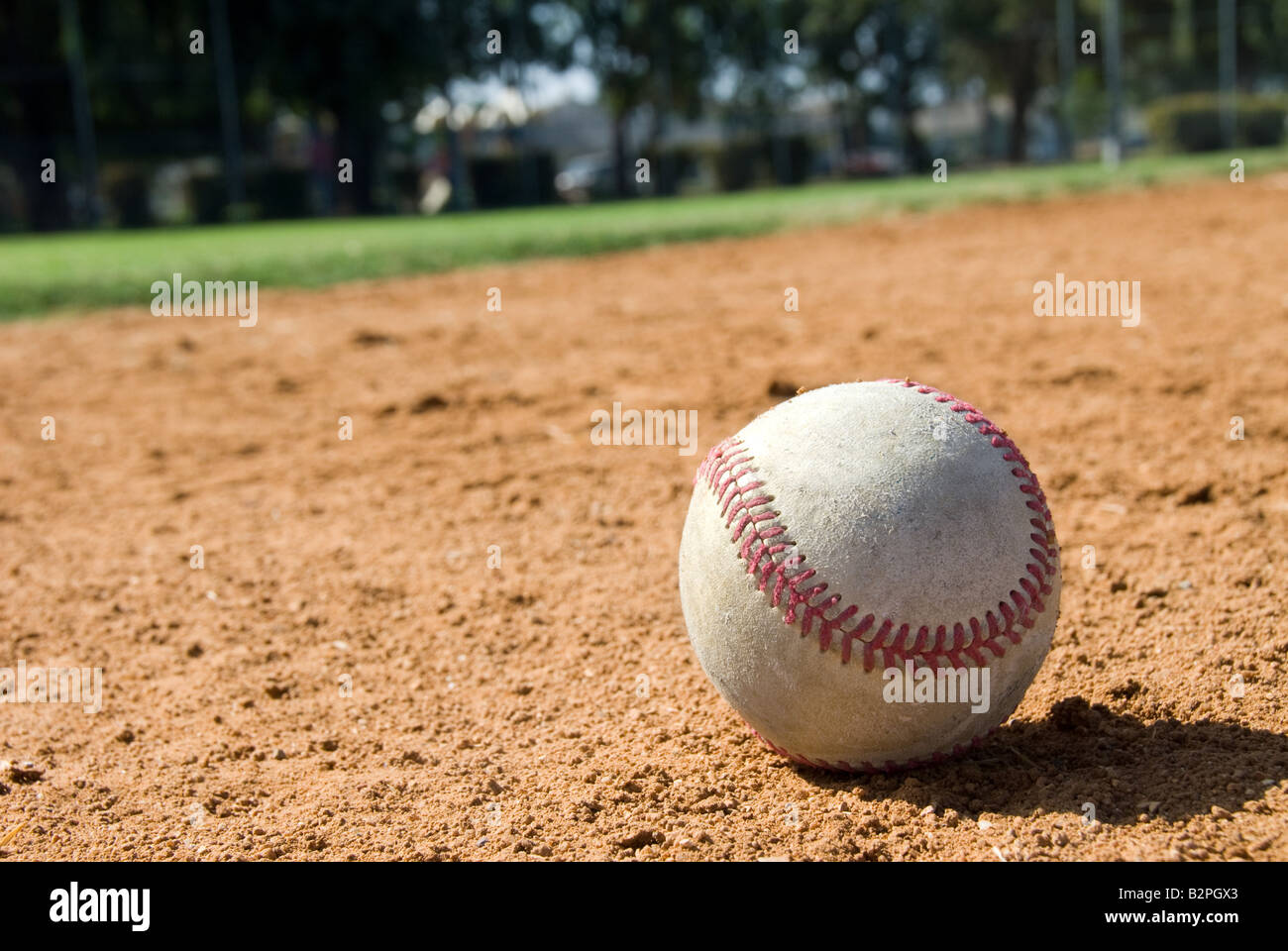 Un baseball risiede nella sporcizia durante una partita di baseball del peering al fuori campo lato Foto Stock
