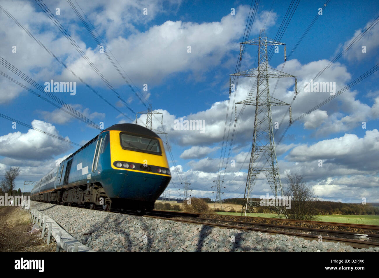 Un treno ad alta velocità passa un traliccio di elettricità Foto Stock