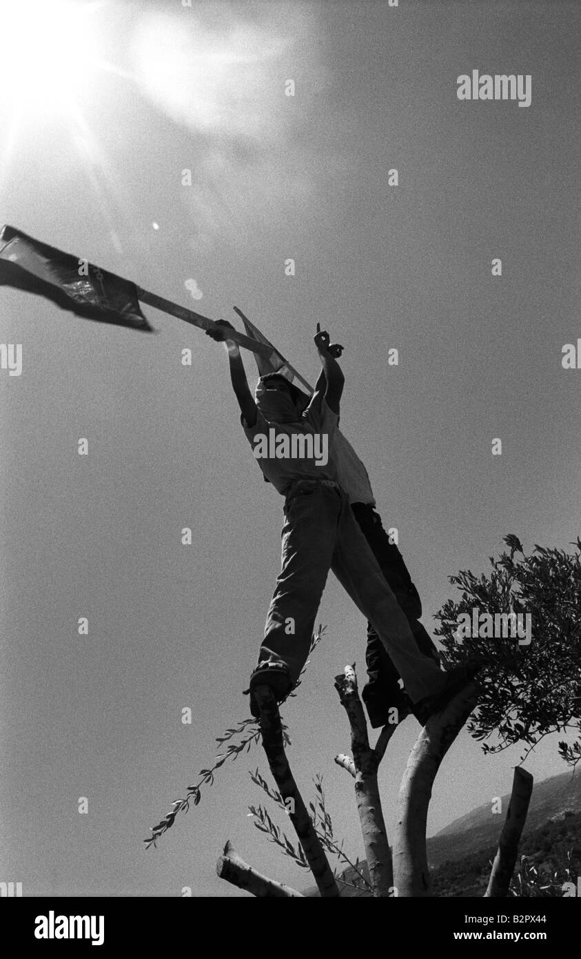 Un giovane manifestante palestinese onde la sua bandiera in defience a oncomming soldati israeliani Foto Stock