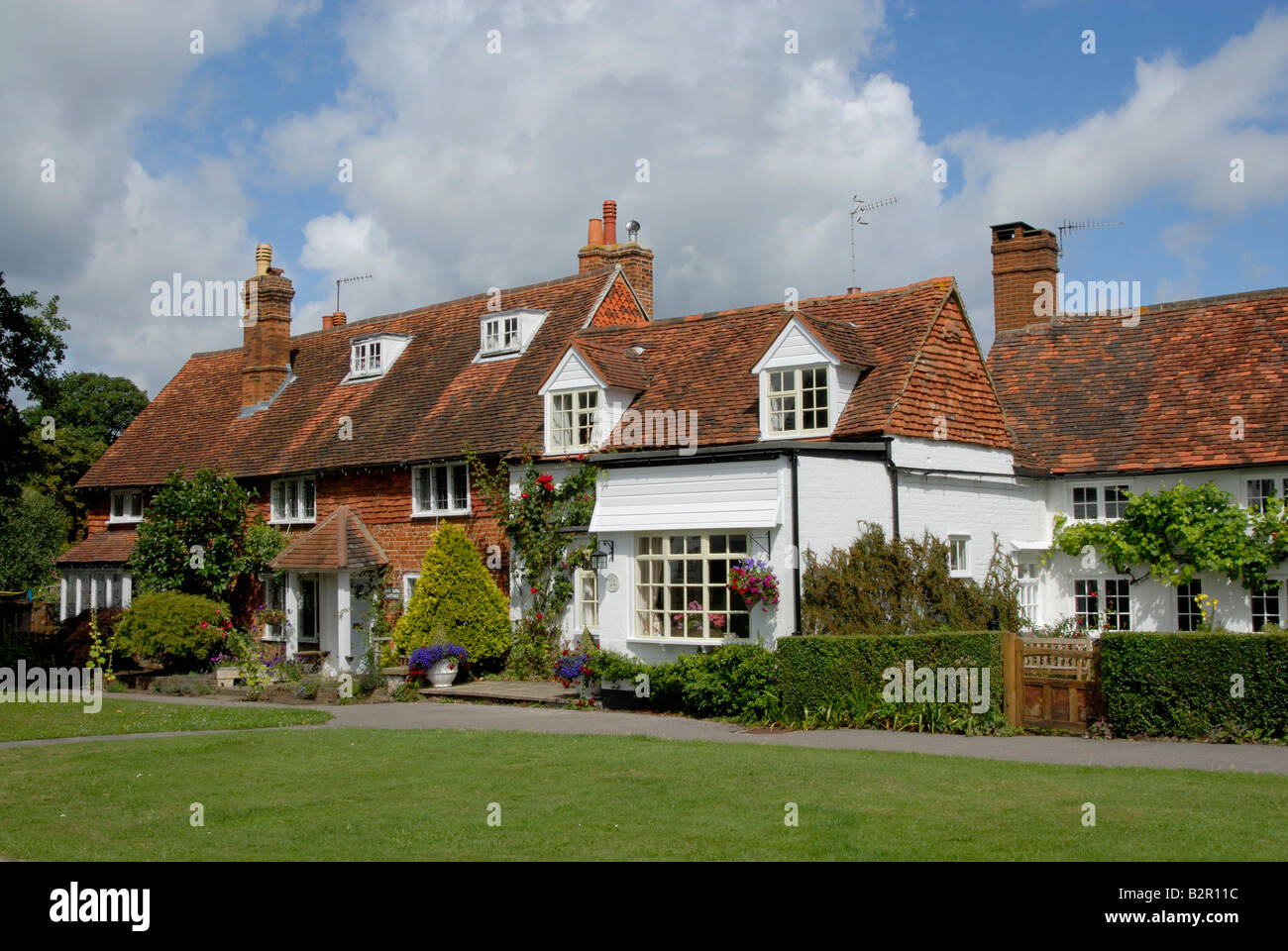 Red mattonelle in terracotta dipinta di bianco e mattone cottages si affaccia Brockham verde, Brockam, Surrey, Inghilterra Foto Stock