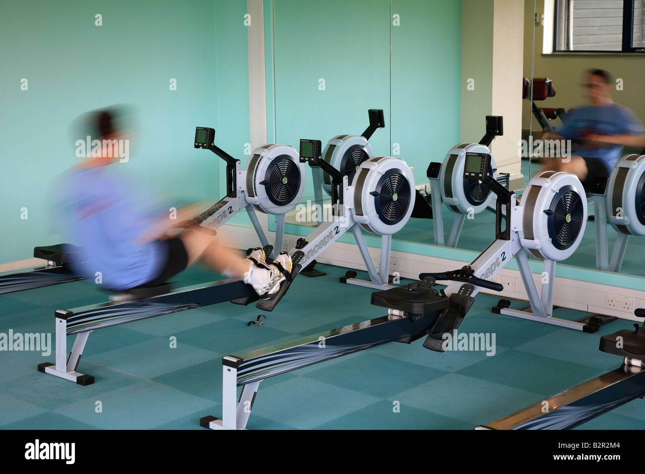 La gente in palestra su vogatori, offuscata per la velocità e la potenza in effetti in un generico Health Spa Foto Stock