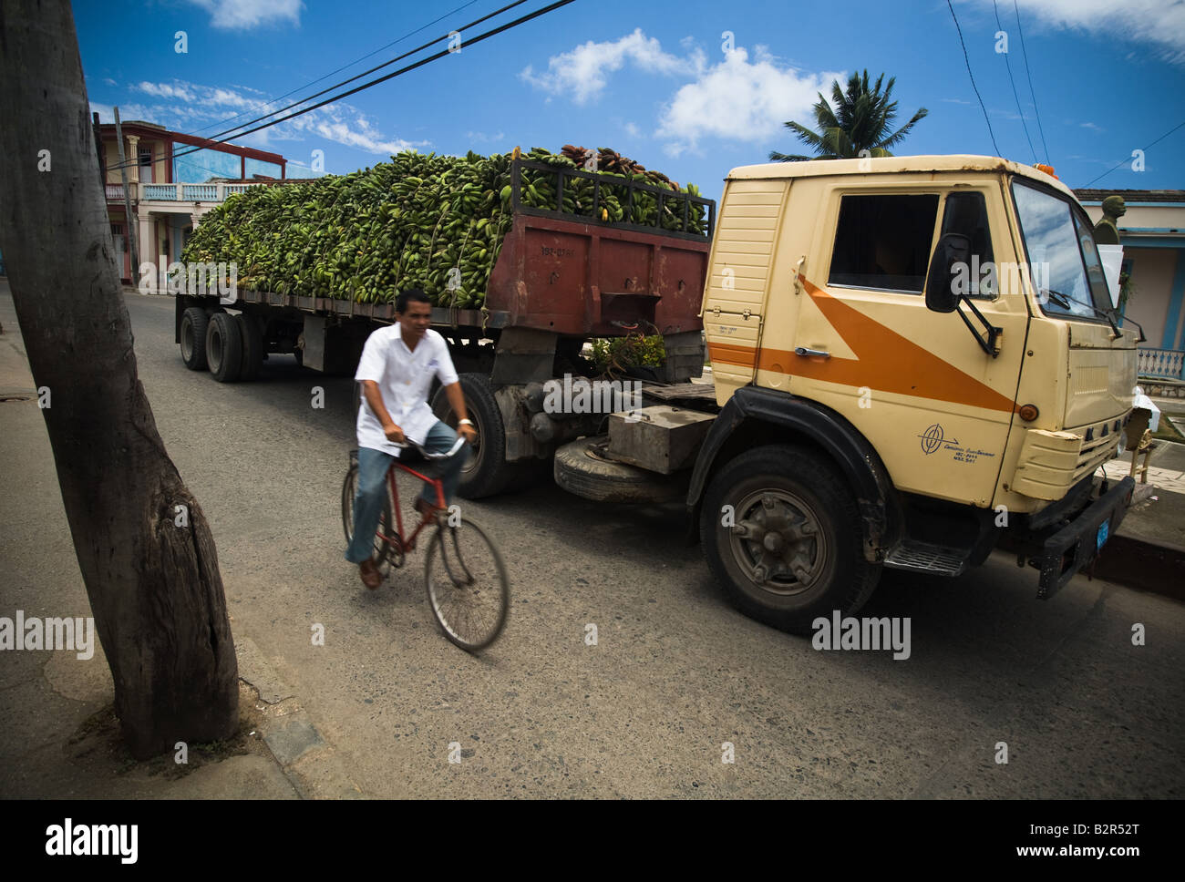 Un uomo che cavalca una bicicletta passato un camion che trasportava un carico di banane in Baracoa Cuba Foto Stock