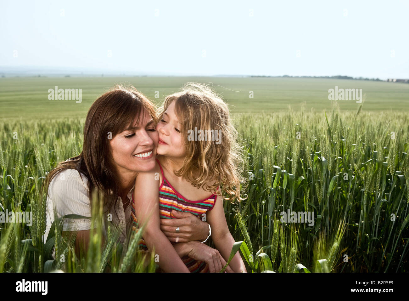 Bambino kissing madre nel campo di grano Foto Stock