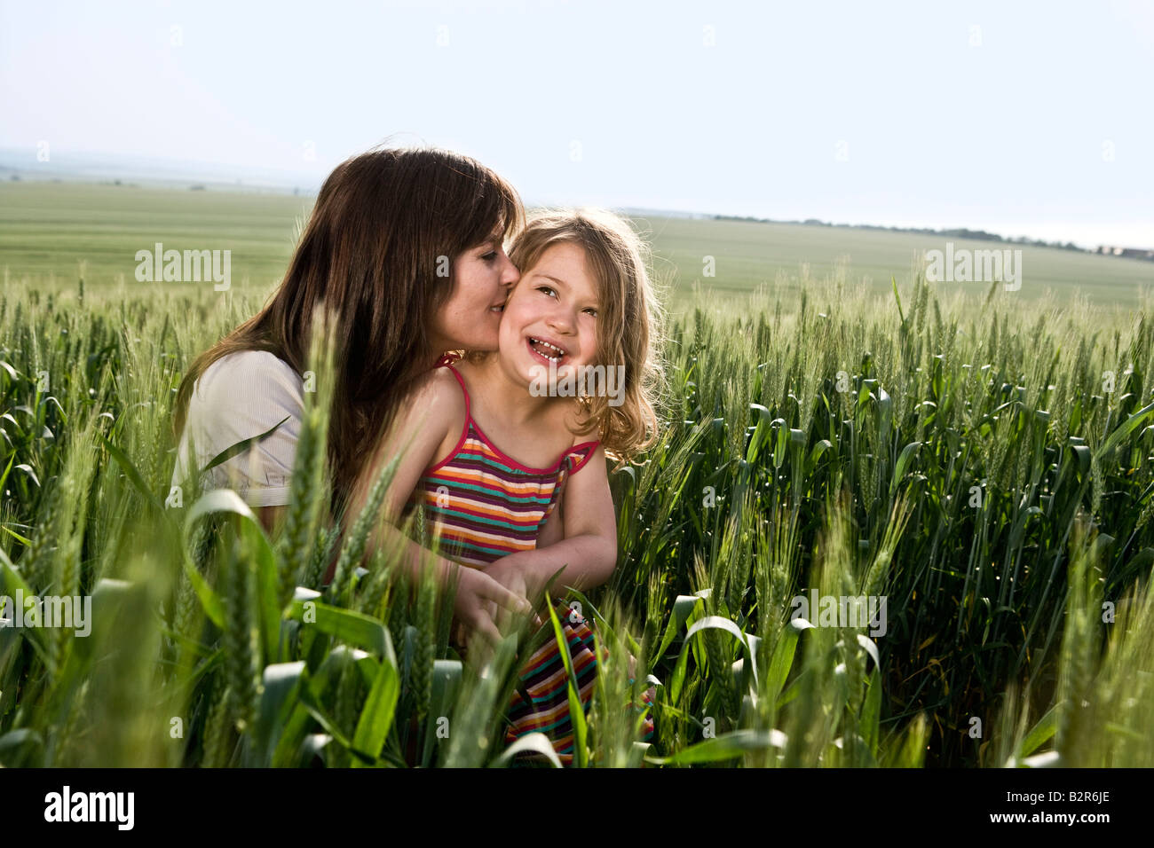 Madre di baciare il bambino nel campo di grano Foto Stock