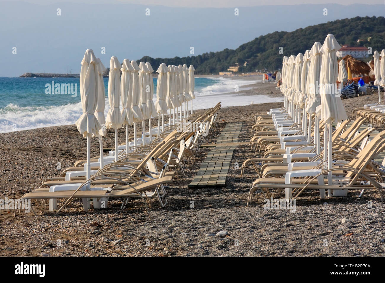 Righe vuote di sedie a sdraio e ombrelloni su una spiaggia organizzata Foto Stock