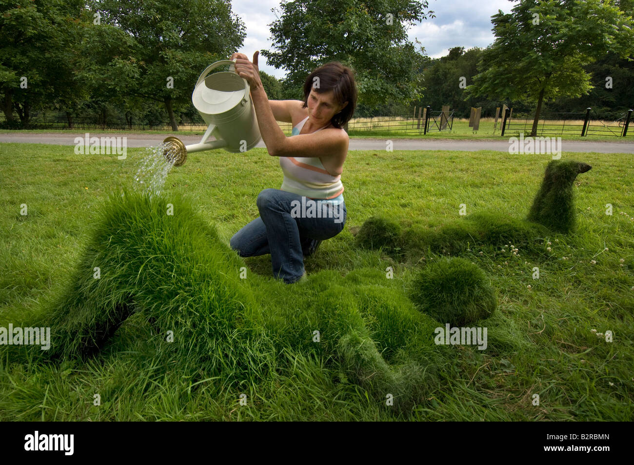 Artista Sharon Baker acque alcune delle sue sculture di erba di figure umane con un annaffiatoio Foto Stock