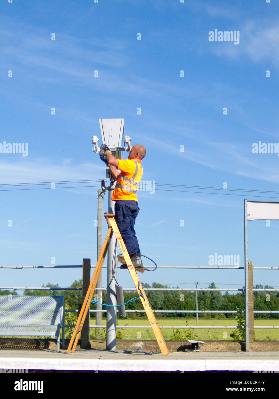 Un ingegnere ferroviario riparazione electroic calendario equipaggiamento su una banchina della stazione, REGNO UNITO Foto Stock