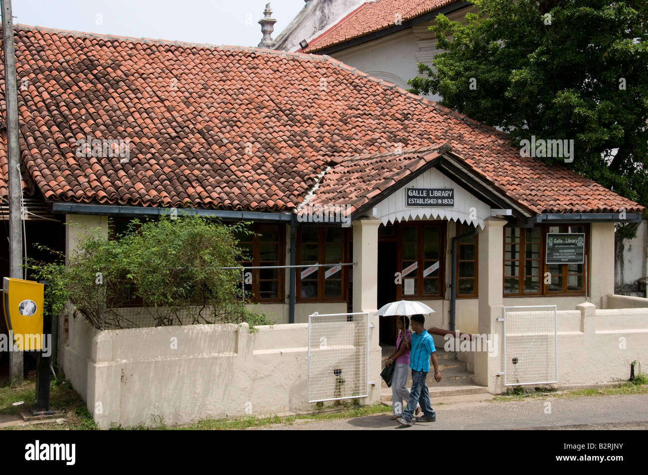 Biblioteca, Forte Galle, Sri Lanka con coppia giovane azienda ombrellone a piedi da Foto Stock