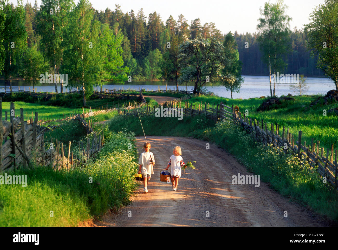 Due bambini andare sulla pesca picnic a camminare sulla strada di campagna nello Småland, Svezia Foto Stock