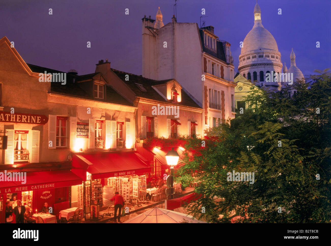 Ristoranti Negozi e turisti a Place du Tertre con il Sacro Cuore di Montmartre a Parigi di notte Foto Stock
