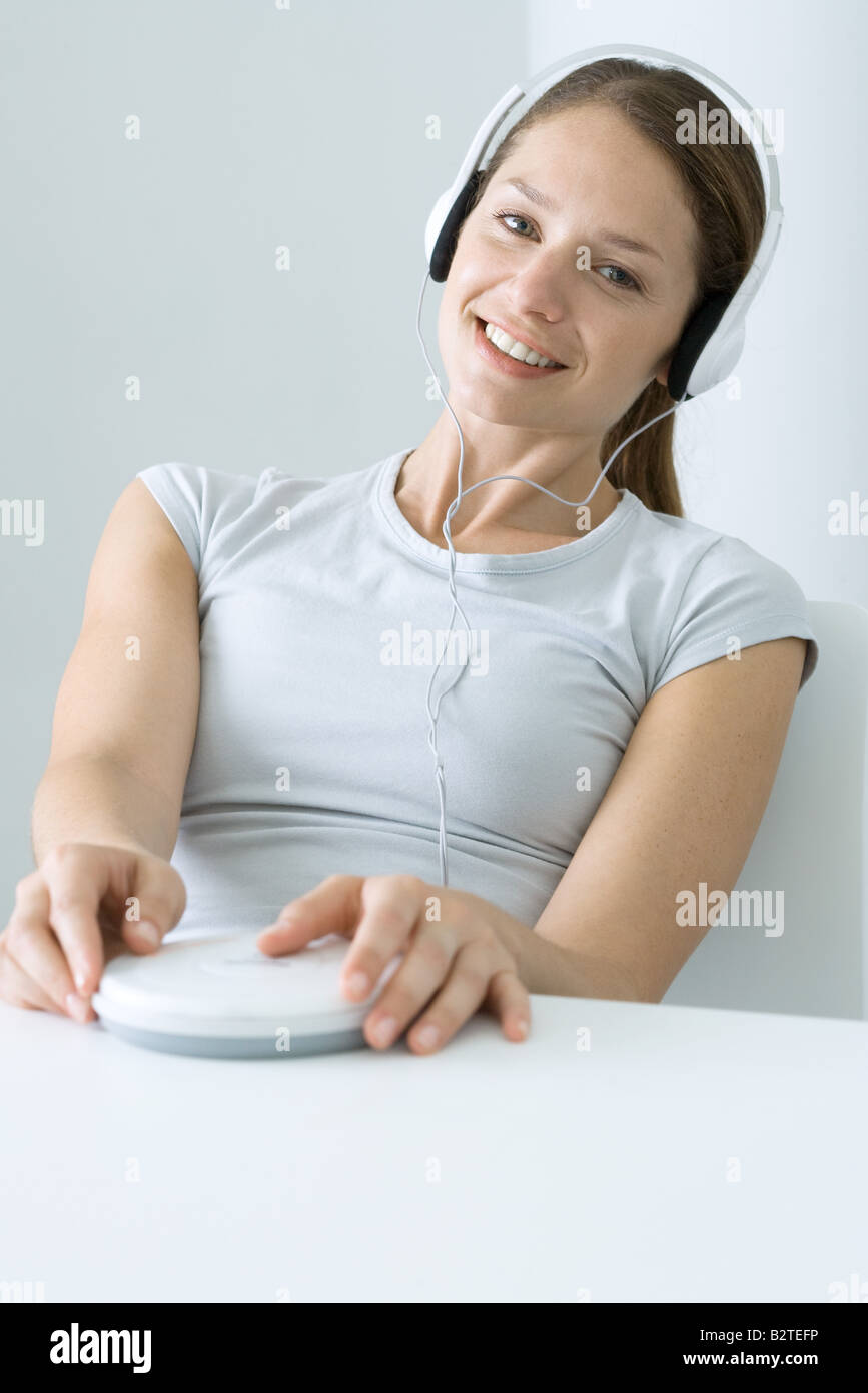 Donna ascolto di lettore CD con le cuffie, sorridente in telecamera Foto Stock