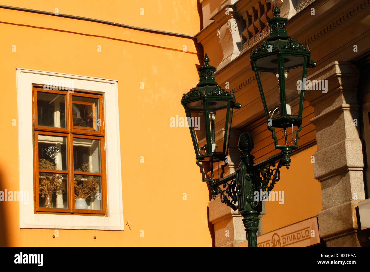 Il vecchio stile street lampada a gas e una illuminata dal sole parete arancione di un edificio con una finestra sulla via Karlova di Praga Foto Stock