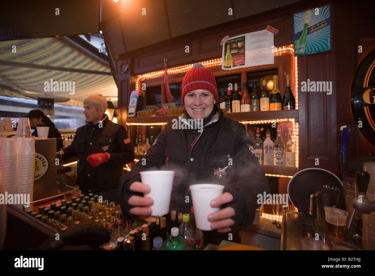 Donna che serve vin brulé mentre sorridente alla fotocamera, Papperla Pub, Zermatt, Vallese, Svizzera Foto Stock