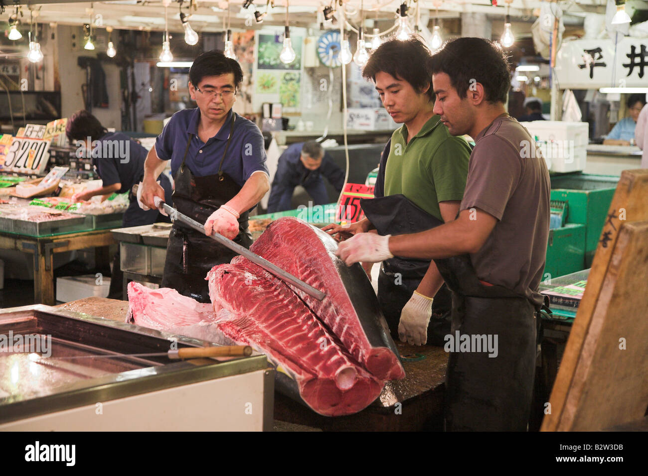 Giapponese dei lavoratori la preparazione di tonno congelato presso la mattina presto il mercato del pesce di Tsukiji a Tokyo. Foto Stock
