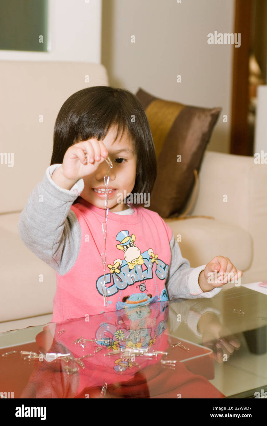 Giovani 4 Anno Vecchio ragazza asiatica giocando con catena a forma di graffetta Foto Stock