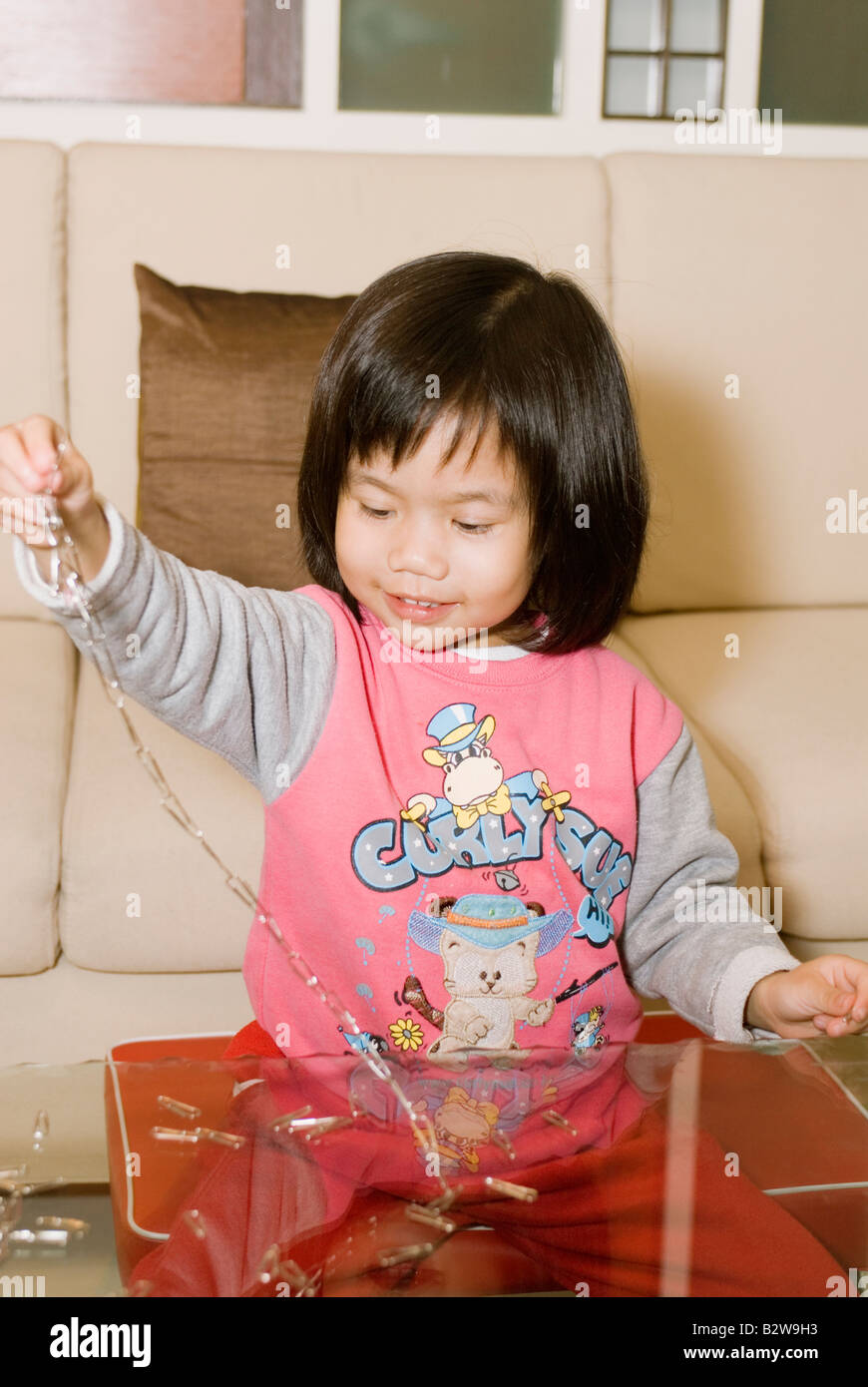 Giovani 4 Anno Vecchio ragazza asiatica giocando con catena a forma di graffetta Foto Stock