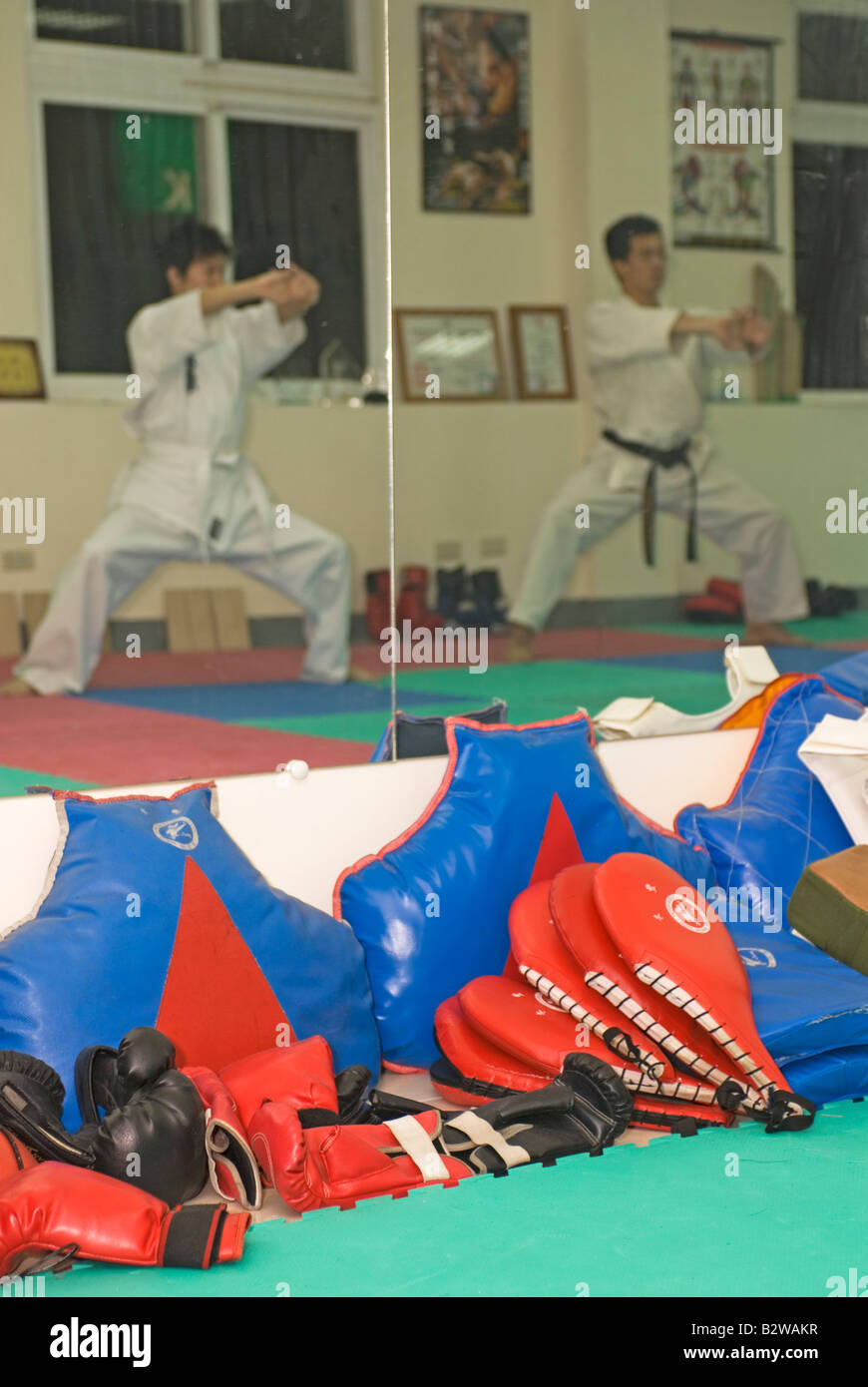 La riflessione a specchio di uomini la formazione in classe di karate, Taiwan, Cina Foto Stock