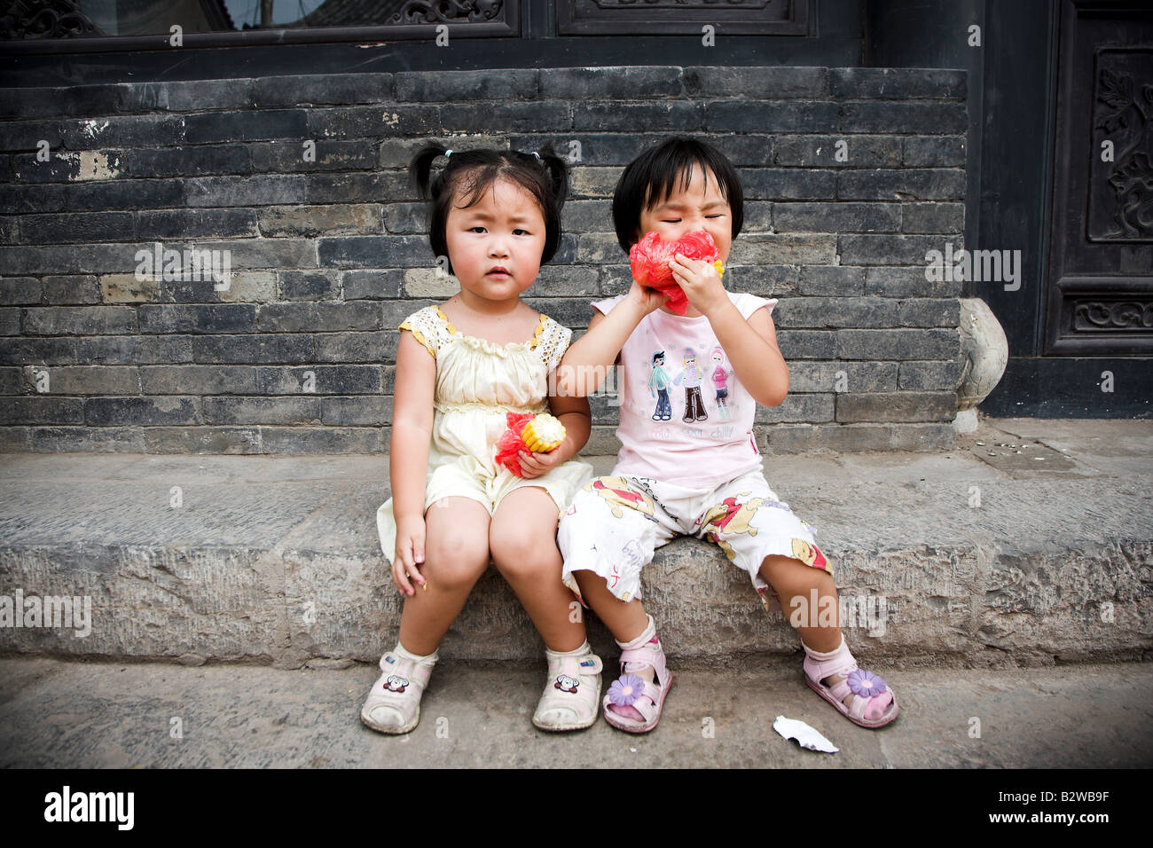 Due giovani ragazze cinesi di mangiare uno spuntino sulla strada a Pingyao, nella provincia di Shanxi in Cina. Foto Stock