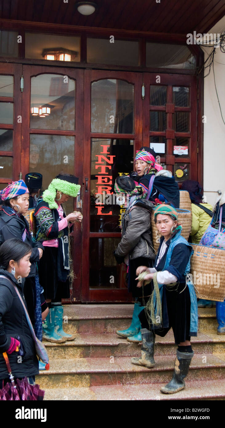 Nero hilltribe Hmong donne folla outswide Sapa alberghi spera di vendere ninnoli e mestieri Vietnam Foto Stock