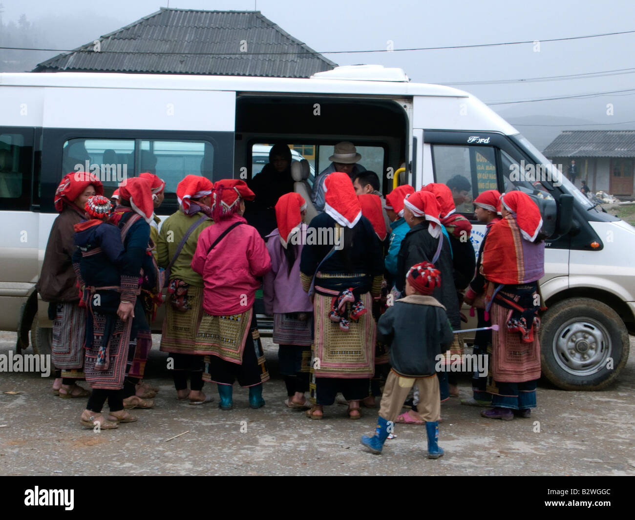 Red Dzao hilltribe donne clamore intorno i turisti e i bus turistici a vendere artigianato Ta Phin villaggio nei pressi di Sapa Vietnam Foto Stock