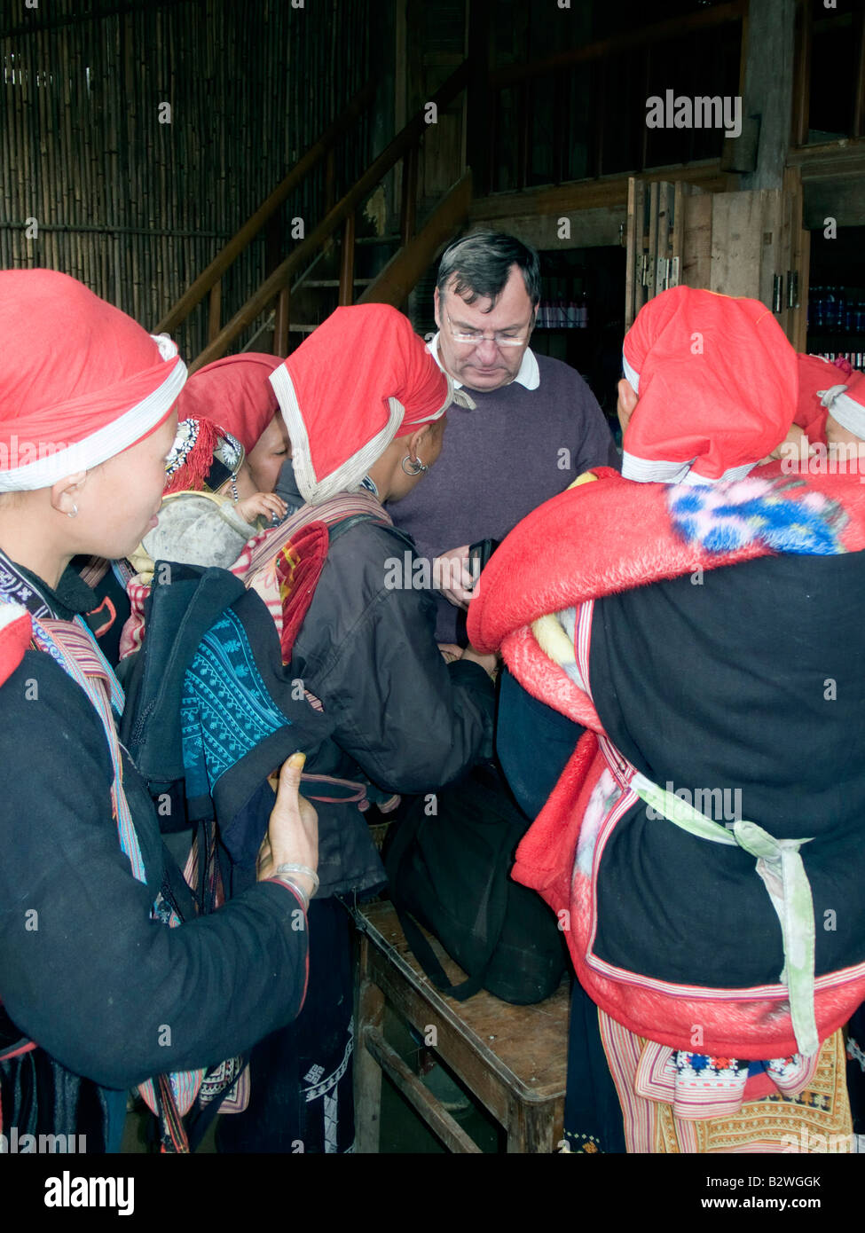 Red Dzao hilltribe donne clamore intorno i turisti e i bus turistici a vendere artigianato Ta Phin villaggio nei pressi di Sapa Vietnam Foto Stock