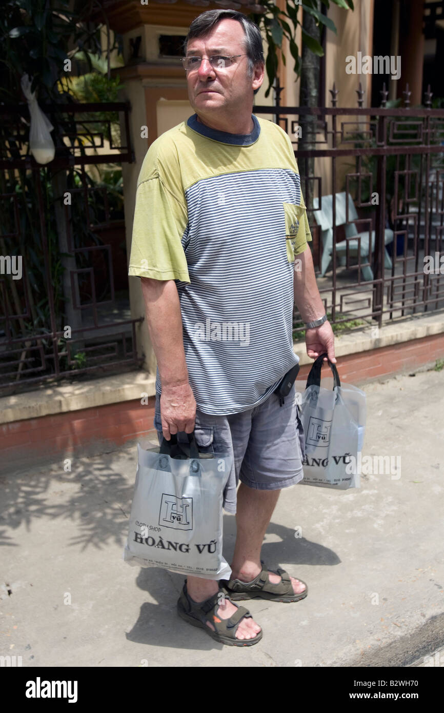 Uomo con custom tailor made vestiti in borse della spesa storica Hoi An  Vietnam Foto stock - Alamy