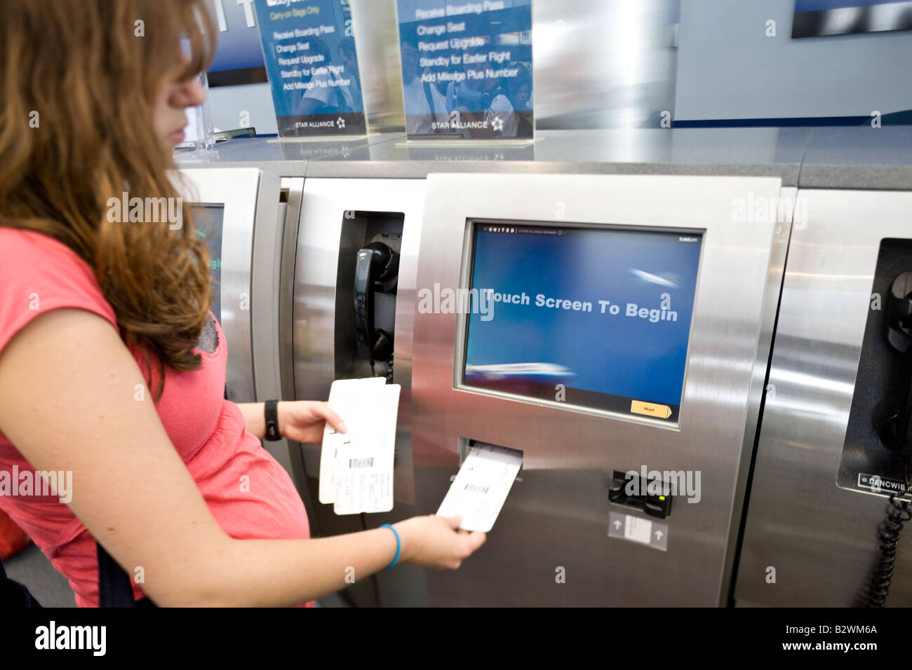 Ragazza con carta di imbarco in automatico di check in macchina, l'Aeroporto Internazionale di Denver, Colorado, STATI UNITI D'AMERICA Foto Stock
