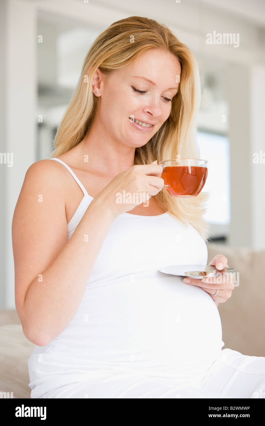 Donna incinta con tazza di tè sorridente Foto Stock