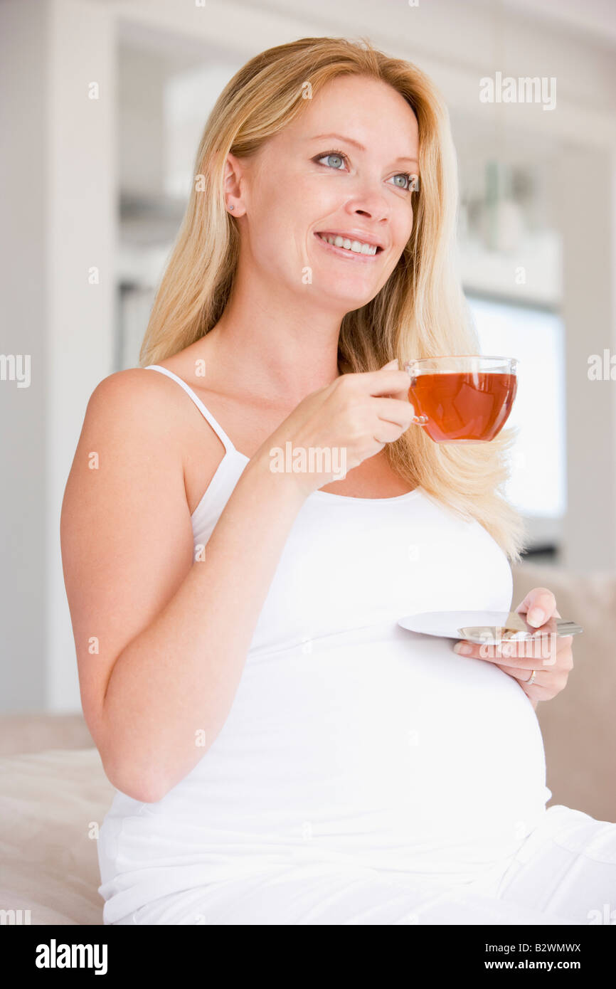 Donna incinta con tazza di tè sorridente Foto Stock