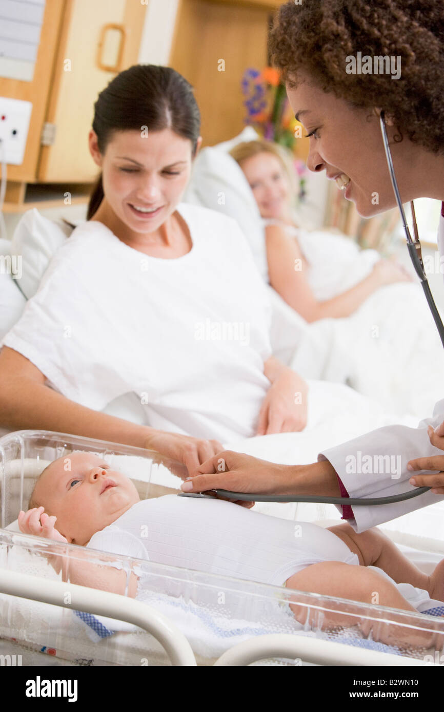 Il controllo medico del bambino con heartbeat nuova madre guarda e sorridente Foto Stock