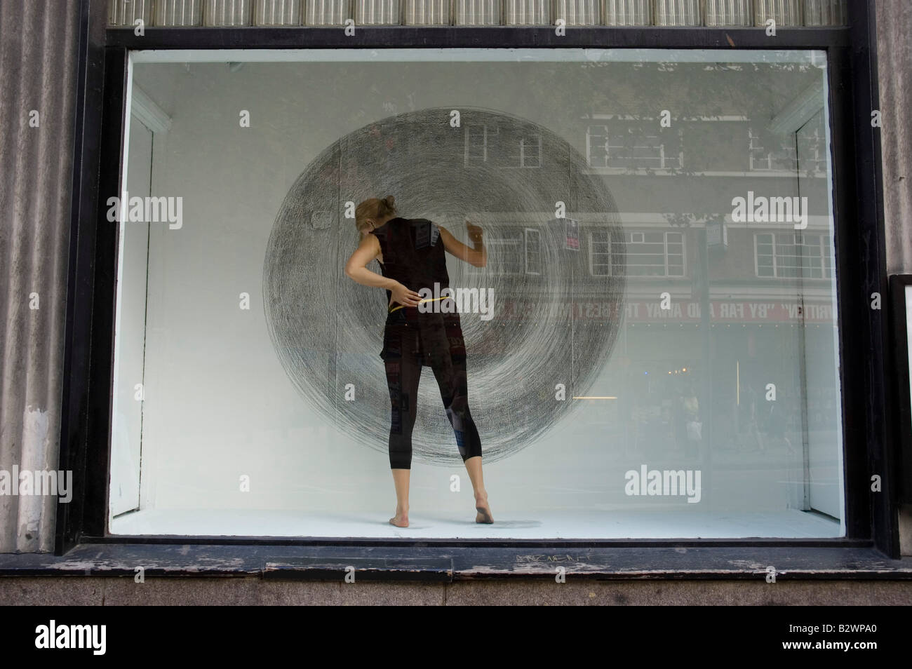 Artista esegue la sua opera in una finestra al Central Saint Martin's su Charing Cross Road, Londra Foto Stock