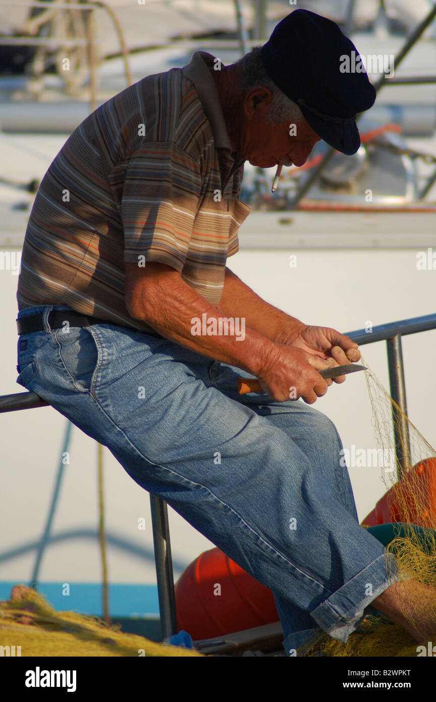 Candide foto di un vecchio pescatore greco riassettando le reti. Foto Stock