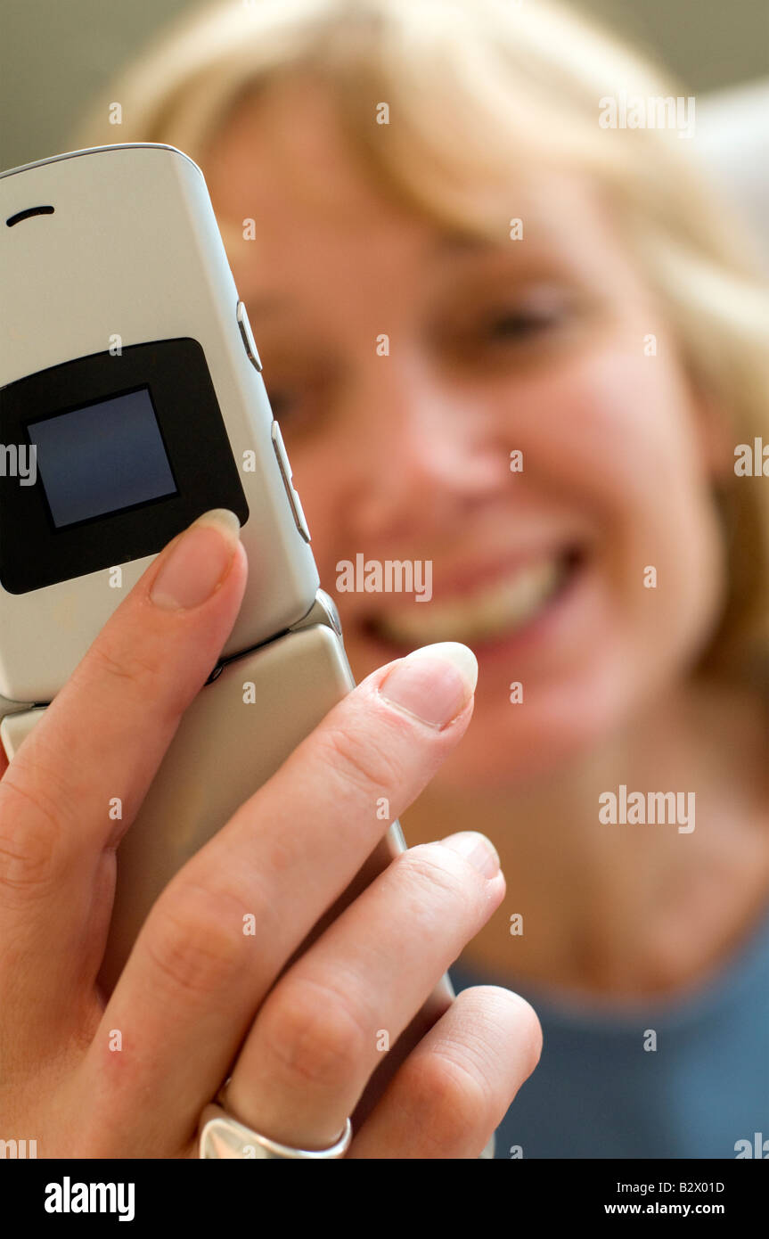 Un attraente bionda di mezza età della donna a parlare su un telefono cellulare. Girato con la profondità di campo minima. Focus è sul telefono. Foto Stock