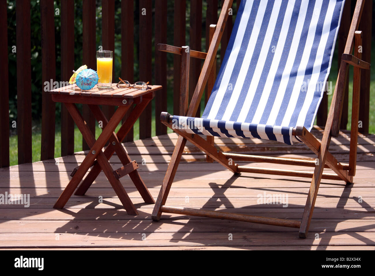 Una sedia in estate su un deck di mattina con succo di arancia Foto Stock